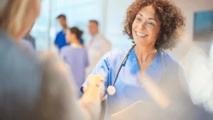 A Nurse wearinga blue Leadcare Recruitment Northern Ireland Uniform, shaking a hand of a male patient. 