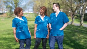 Three Leadcare Nurses in blue Leadcare scrubs standing together during their lunch break, smiling outside a healthcare facility in Northern Ireland.