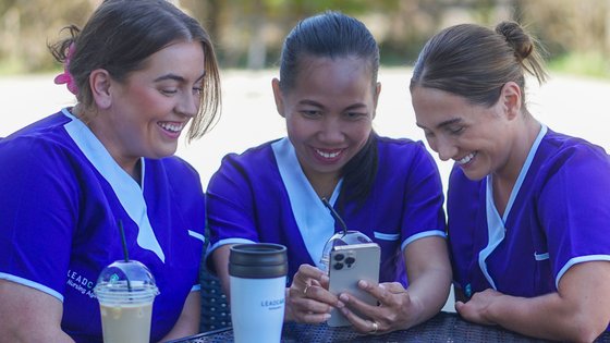 Three healthcare assistants looking at a phone